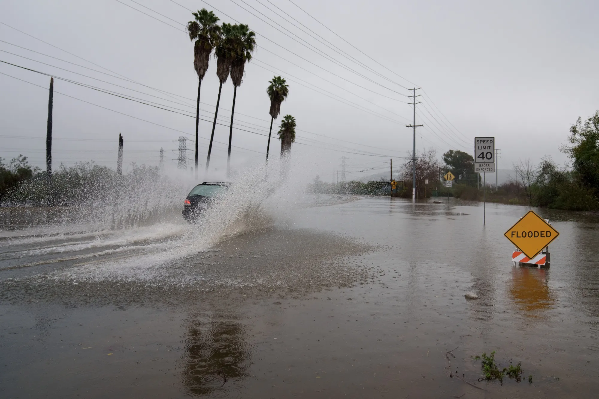 A vehicle drives through a flooded street during a storm in Whittier, California.