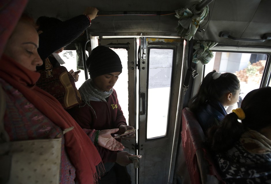 Suraj Shrestha (C), the conductor of a women-only bus, collects the bus fare from a passenger in Kathmandu January 6, 2015. 