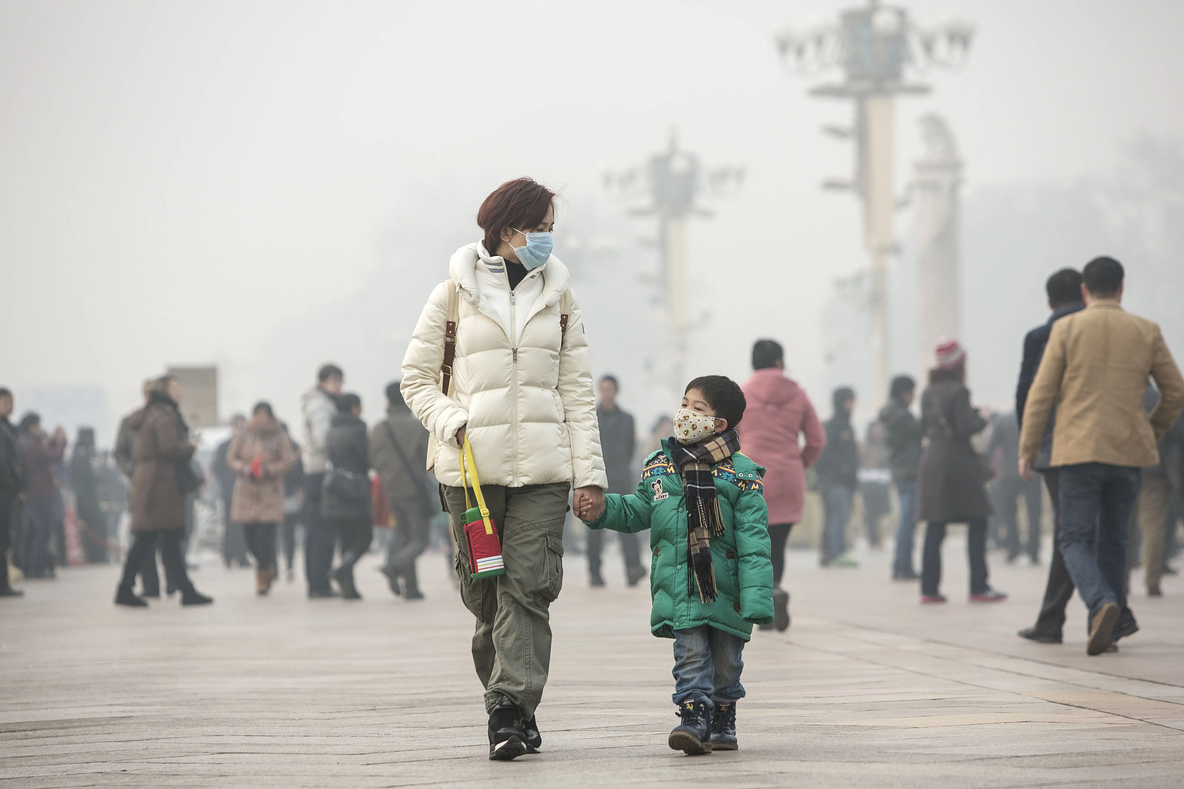 A woman and child wearing face masks walk down a road in Beijing on Monday.

