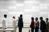 A queue of people wait to be scanned for radiation