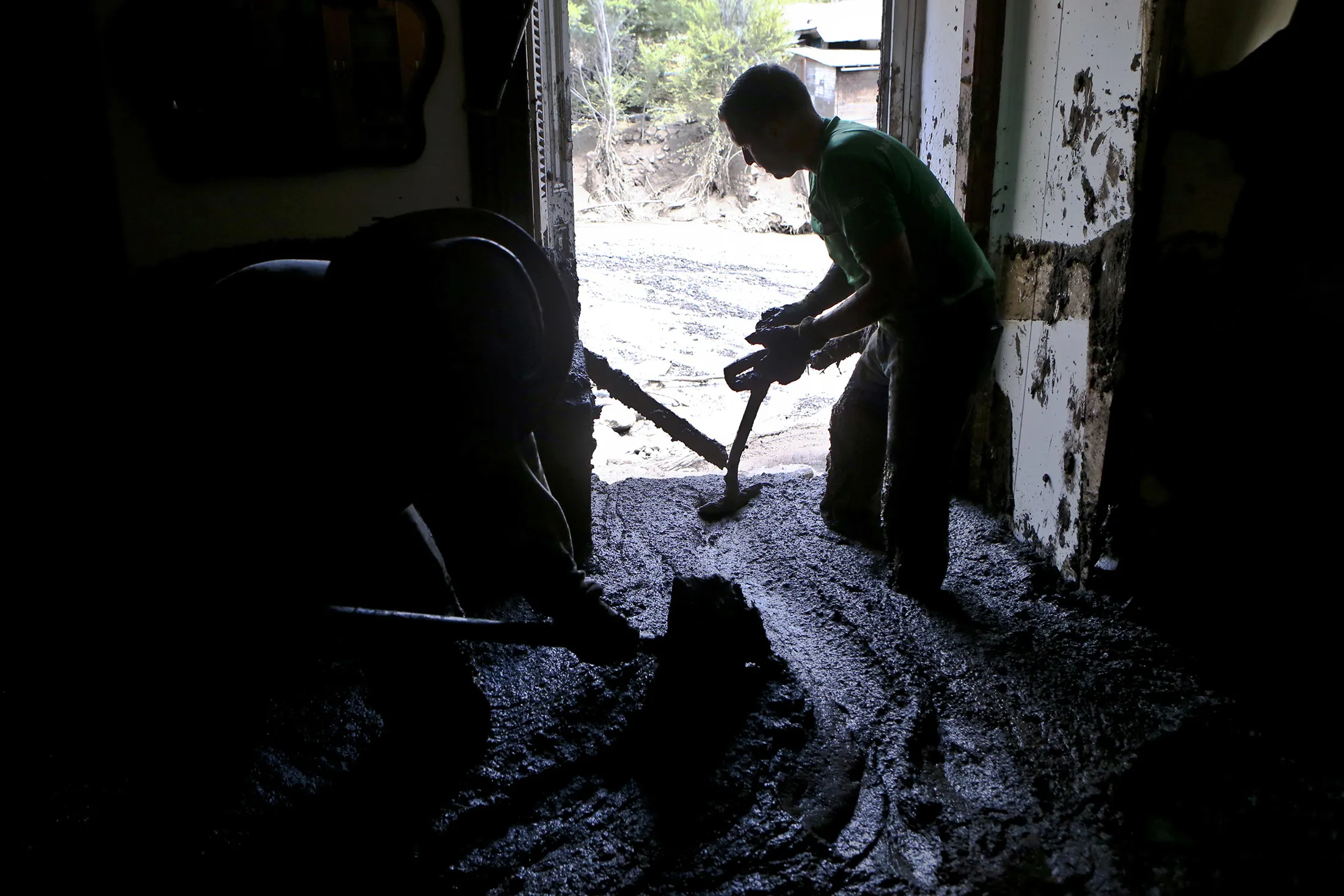 A man shovels mud from a home brought by the overflow of the Estero San Jose River in San Alfonso, Chile, on Feb. 26, 2017.

