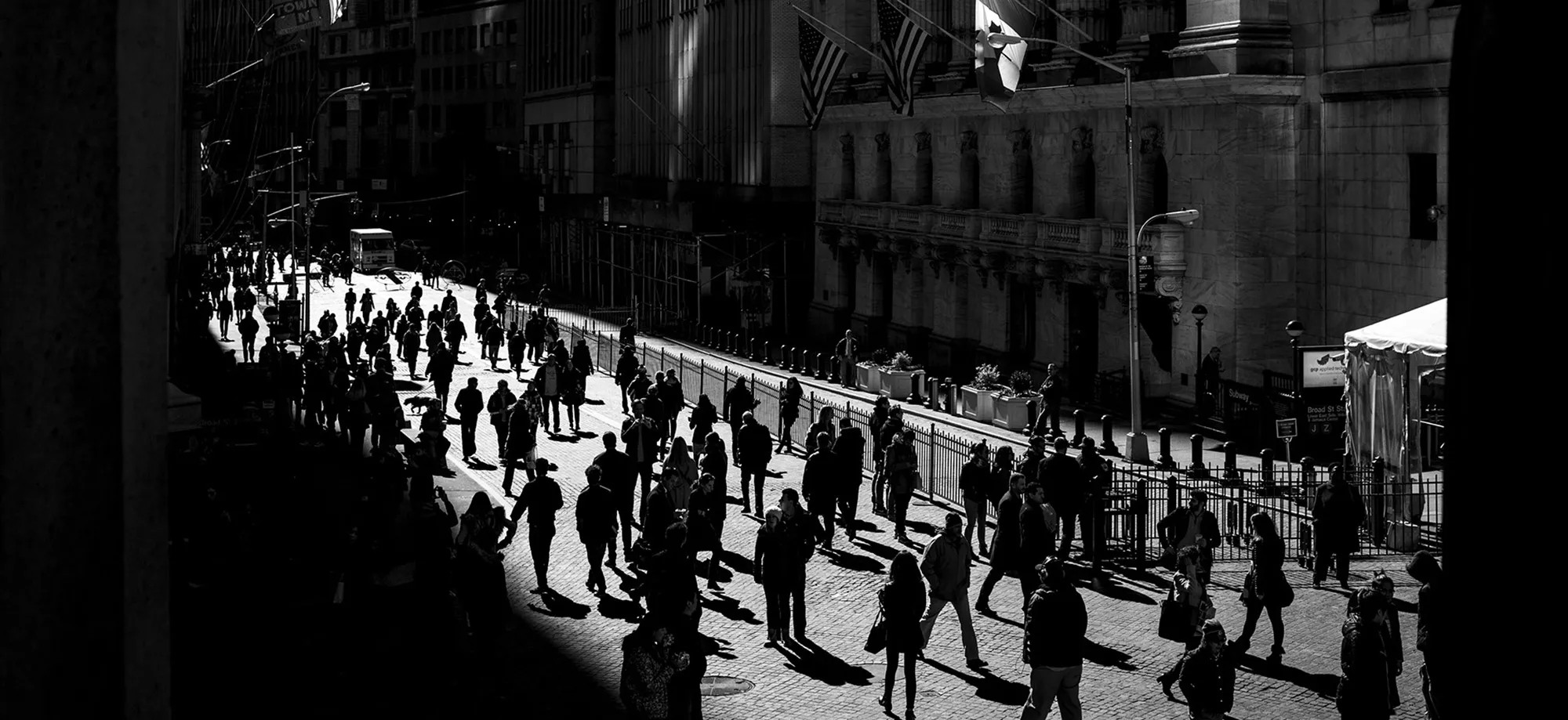 Flags fly as pedestrians walk past the New York Stock Exchange.