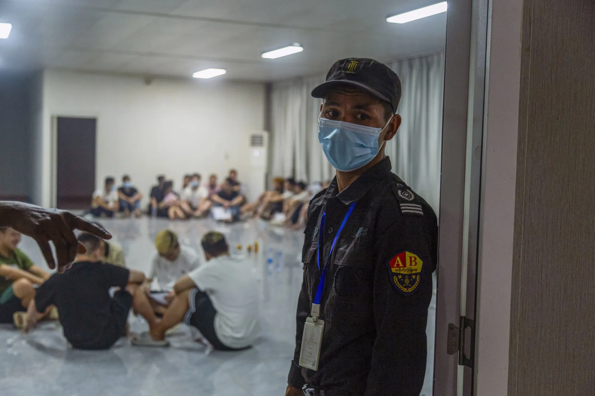 A security guard in font of a room full of alleged scam center workers and victims during a crackdown in Myanmar's eastern Myawaddy township.