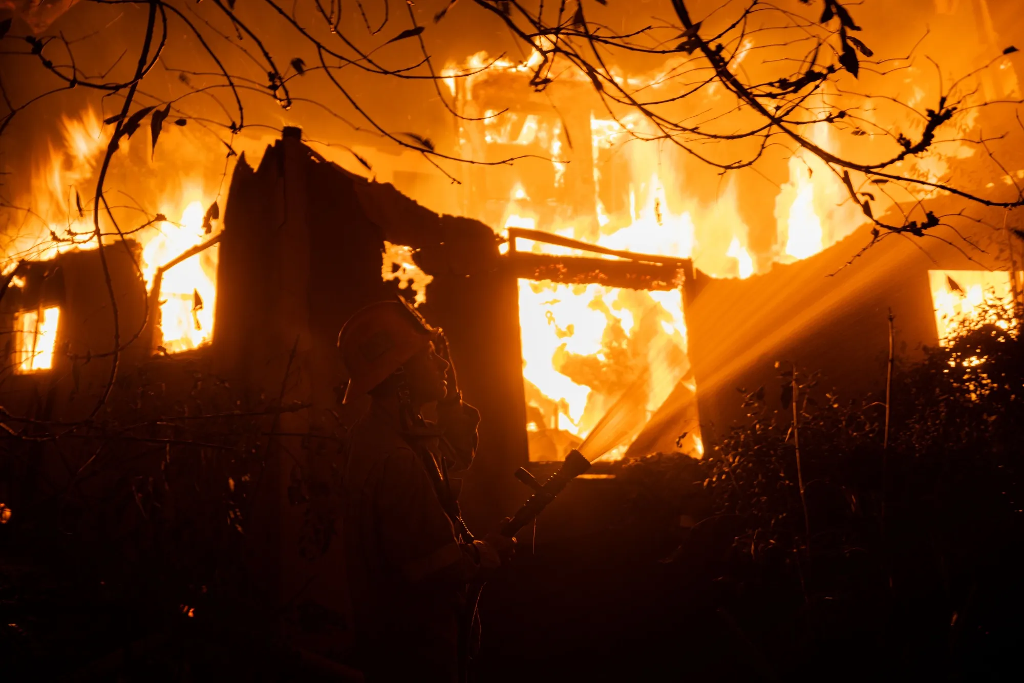 A firefighter hoses down a house during the Eaton Fire in Altadena, California, in January.