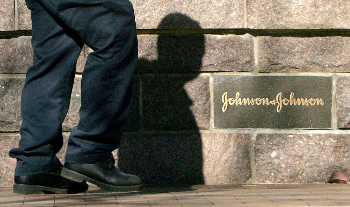A man walks past a Johnson & Johnson sign in front of the company's headquarters in New Brunswick, New Jersey, Monday, November 7, 2005.   Guidant Corp. sued to force Johnson & Johnson to complete a $25.4 billion purchase of the troubled medical-devices maker and reported a plunge in quarterly profit.