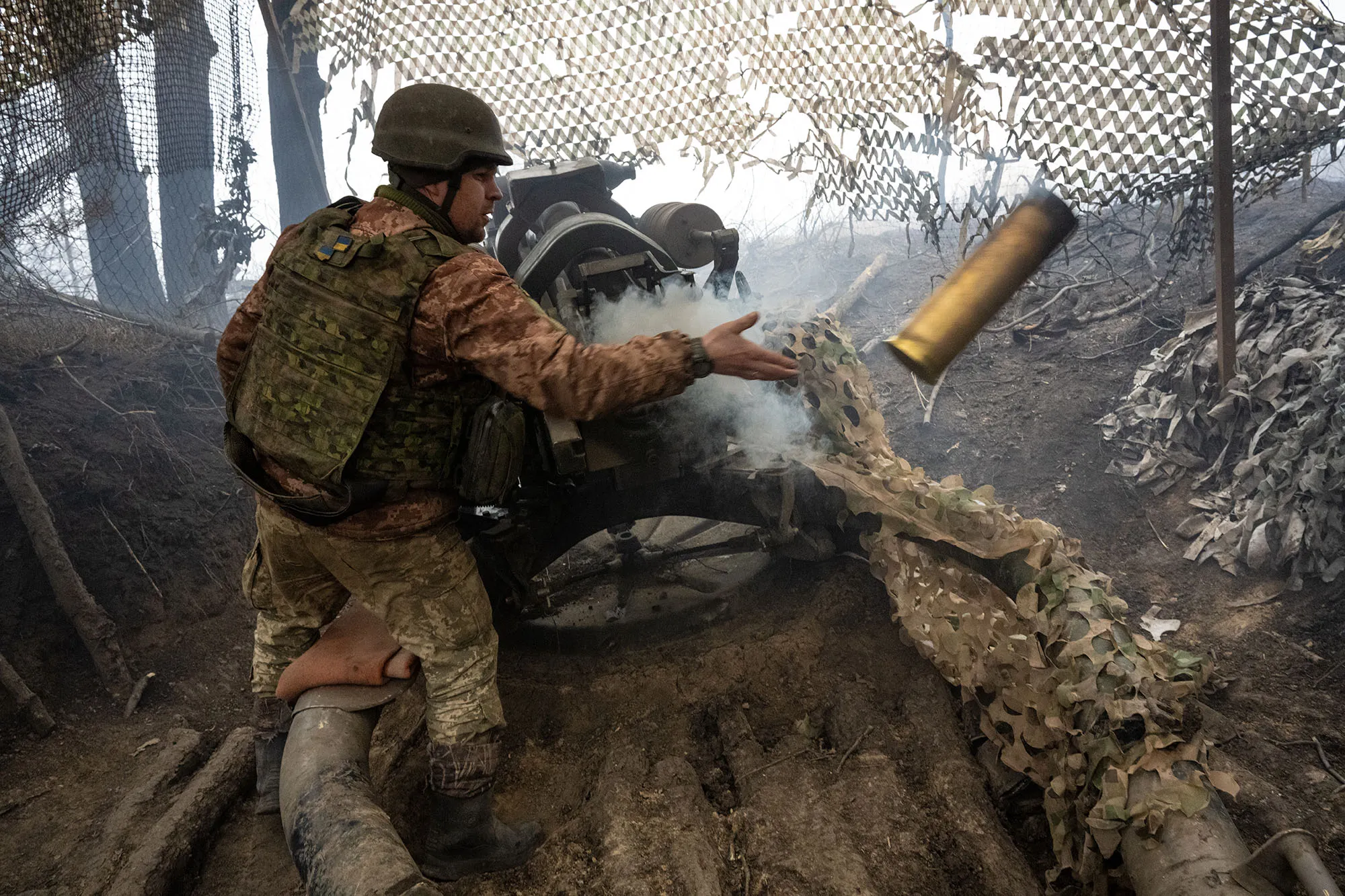 A gunner removes a shell casing after firing the howitzer at Russian positions in&nbsp;Ukraine.