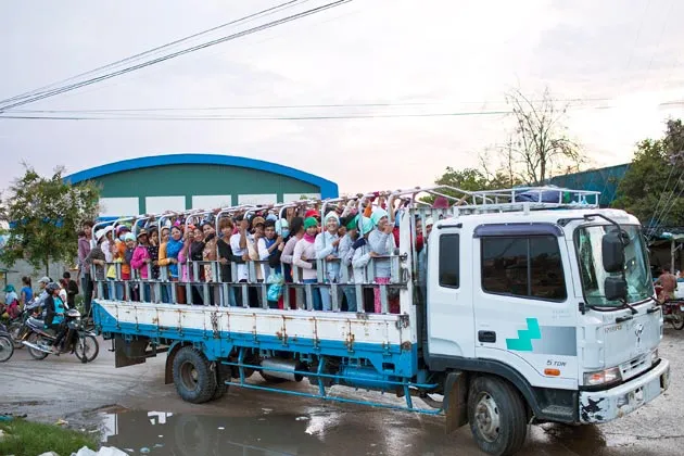 Workers ride on the back of a transport truck at the end of the work day in a garment manufacturing district in Phnom Penh, Cambodia, on July 1, 2013