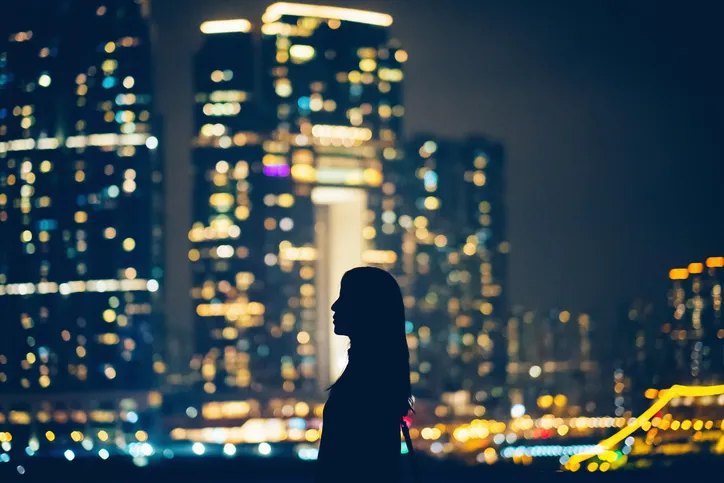 Silhouette of woman standing against beautiful skyline of Hong Kong looking out at city