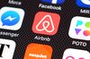 The Airbnb app logo is displayed on an iPhone.