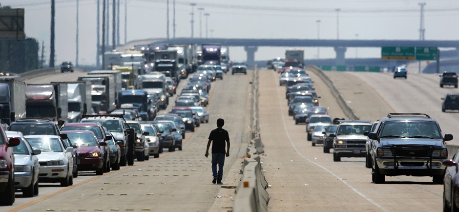 A man walks on a highway in north Houston.