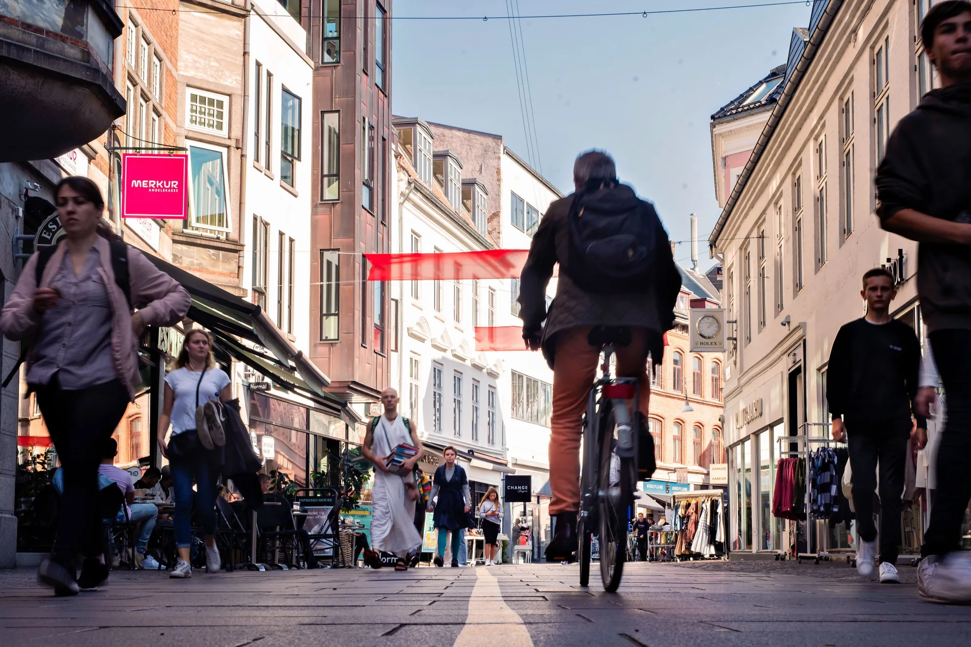 A cyclist and pedestrians make their way along a shopping street in Aalborg, Denmark.