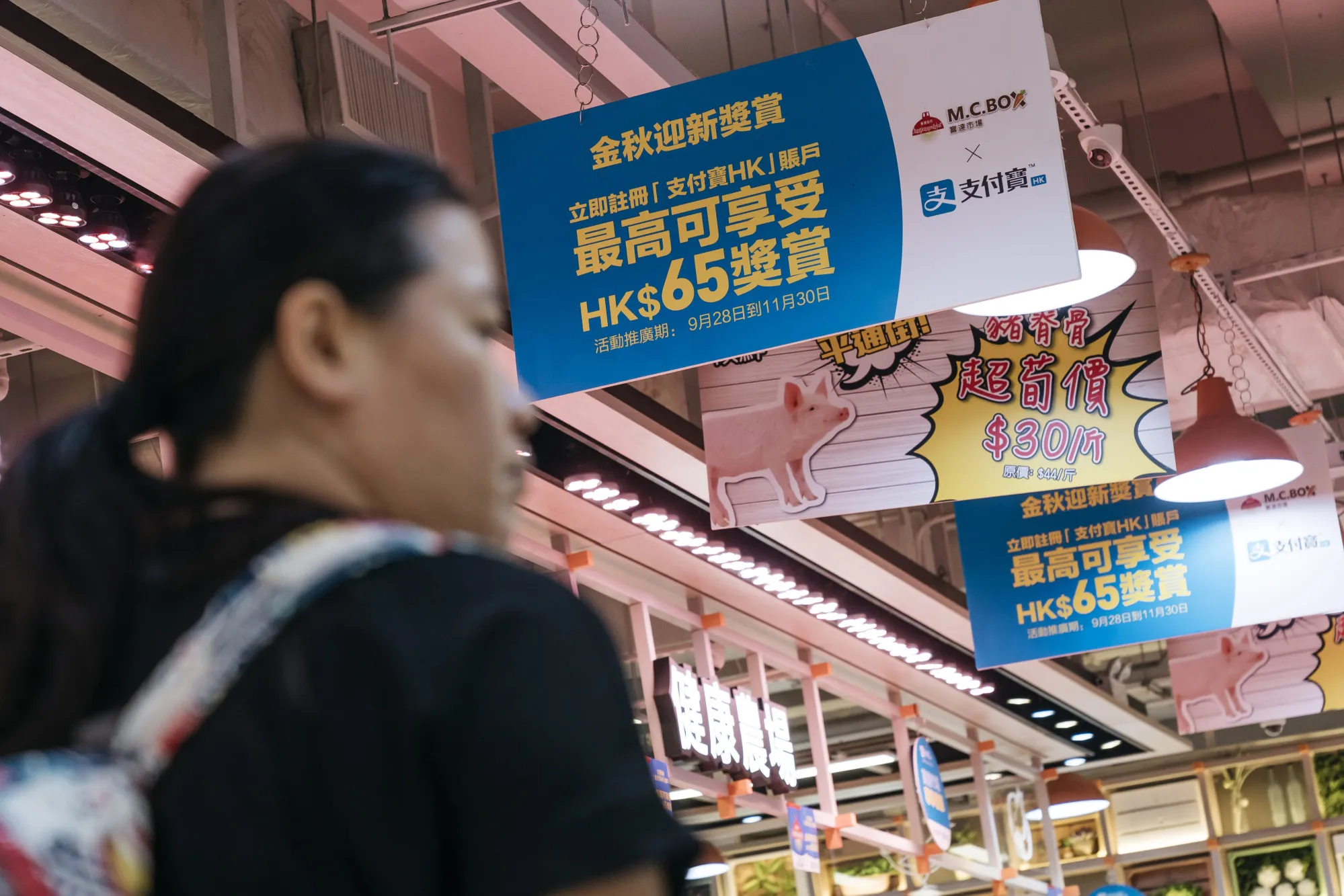 A shopper walks past advertisement banners for for Ant Financial Services Group's Alipay, an affiliate of Alibaba Group Holding Ltd..