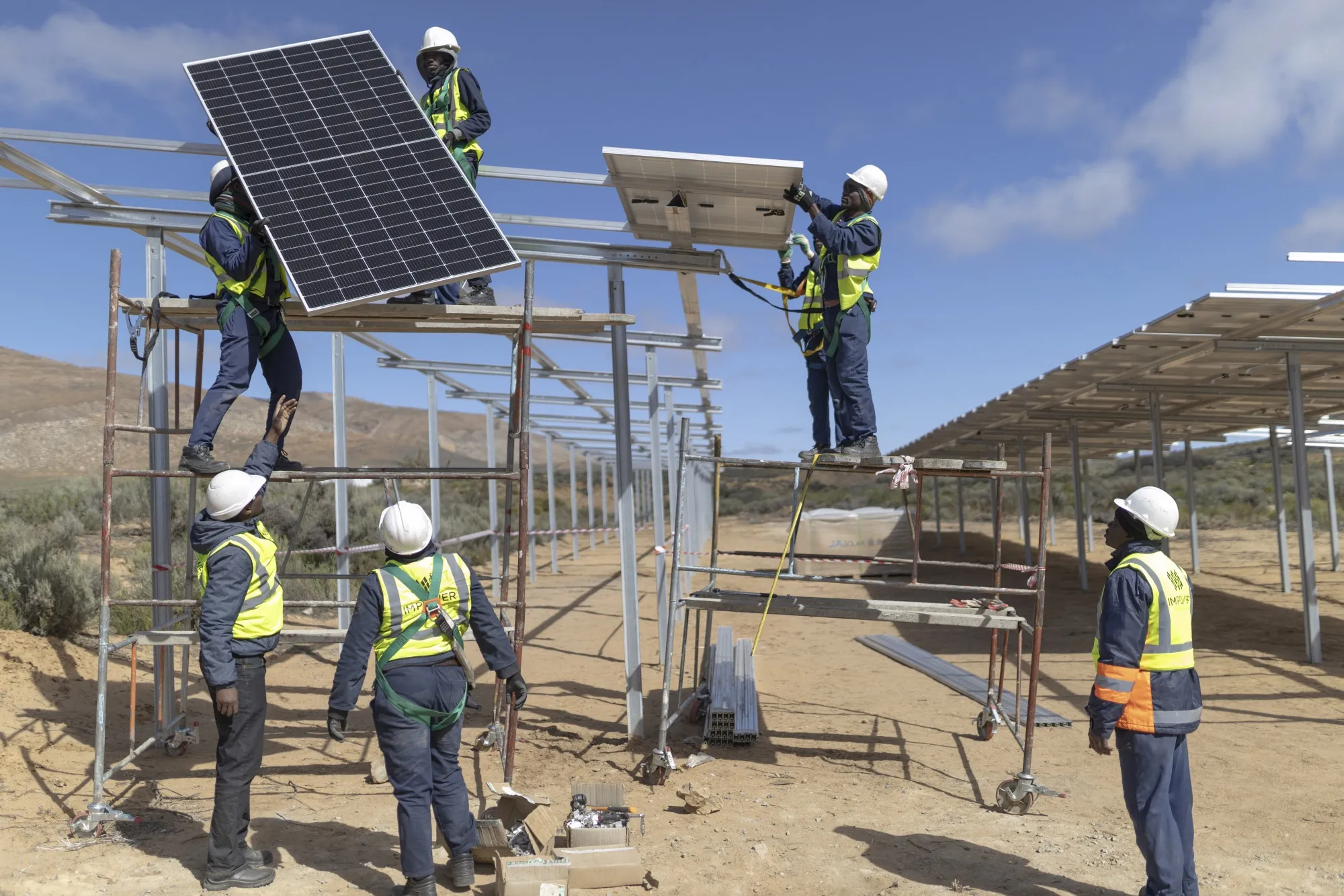 Workers install solar panels at farm in Groenfontein, South Africa.