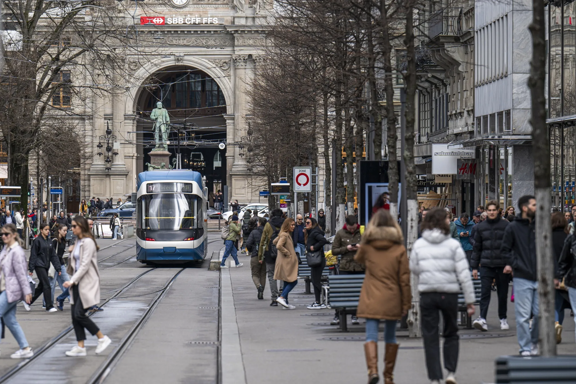The Zurich HB rail station beyond a busy retail street in Zurich.