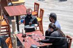 A waiter wearing protective gloves and a mask serves drinks to customers at a restaurant on Pier 39 in San Francisco, California, U.S., on&nbsp;June 22.