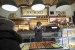 Freshly-baked loaves of bread and pizzas on sale inside the store of a bakery in Rome, Italy.
