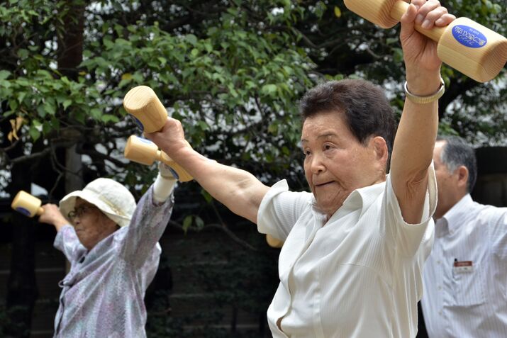 Elderly people work out with wooden dumb
