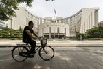 A man rides a bicycle past the People's Bank of China (PBOC) headquarters in Beijing, China.
