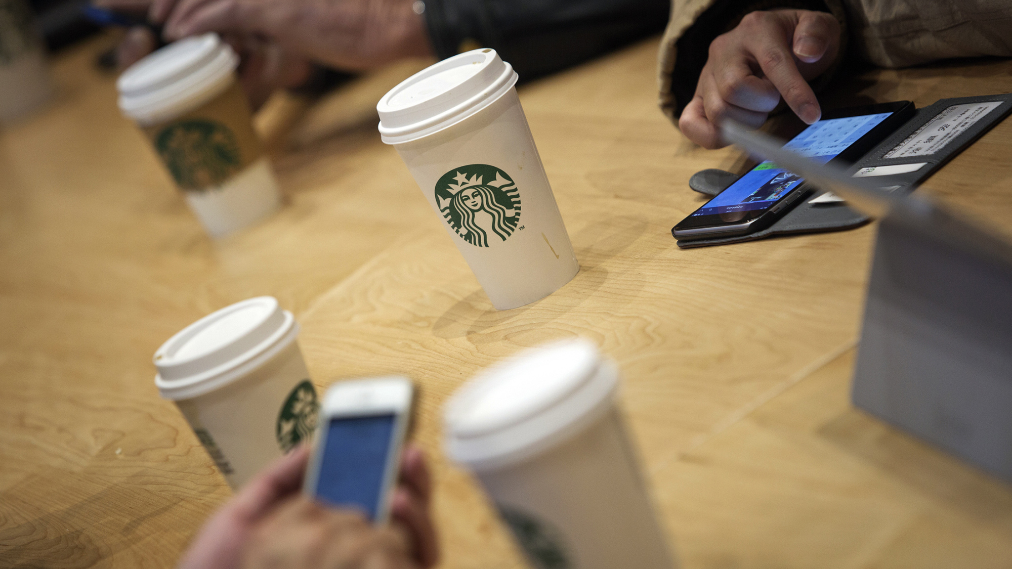 Customers use mobile devices inside a Starbucks Corp. coffee shop.
