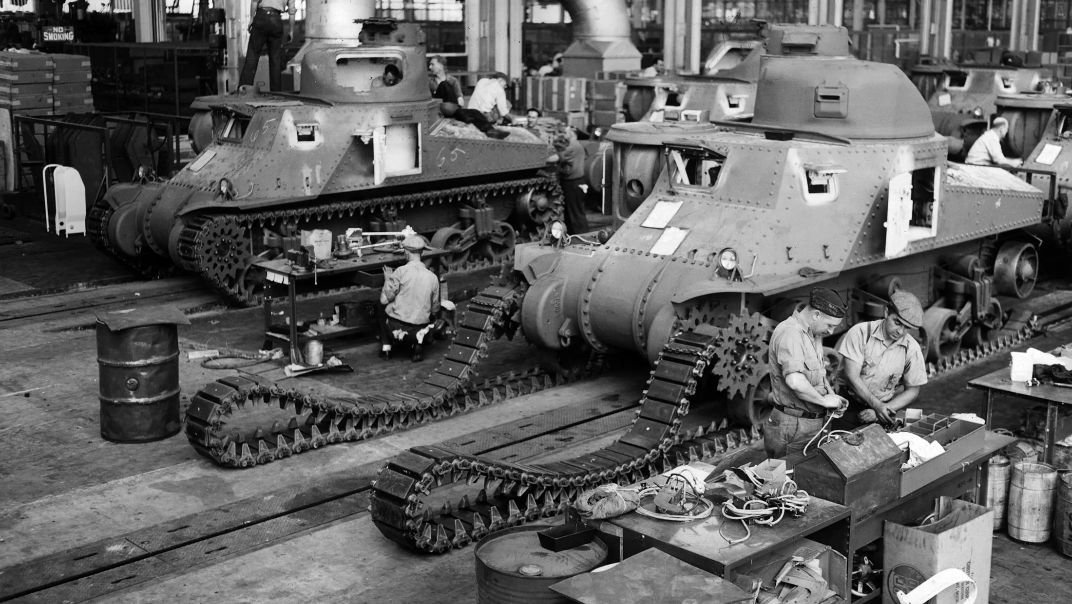 circa 1942: A full-length view of uniformed male workers assembling M-3 tanks in an American factory during World War II, 1940s.

