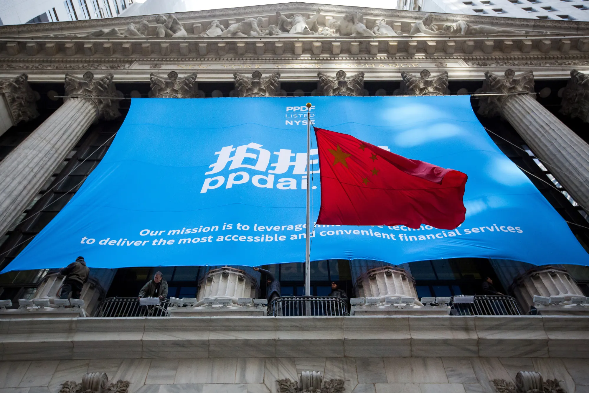 The People's Republic of China flag flies in front of PPDAI Group Inc. signage displayed outside of the New York Stock Exchange (NYSE) in New York.