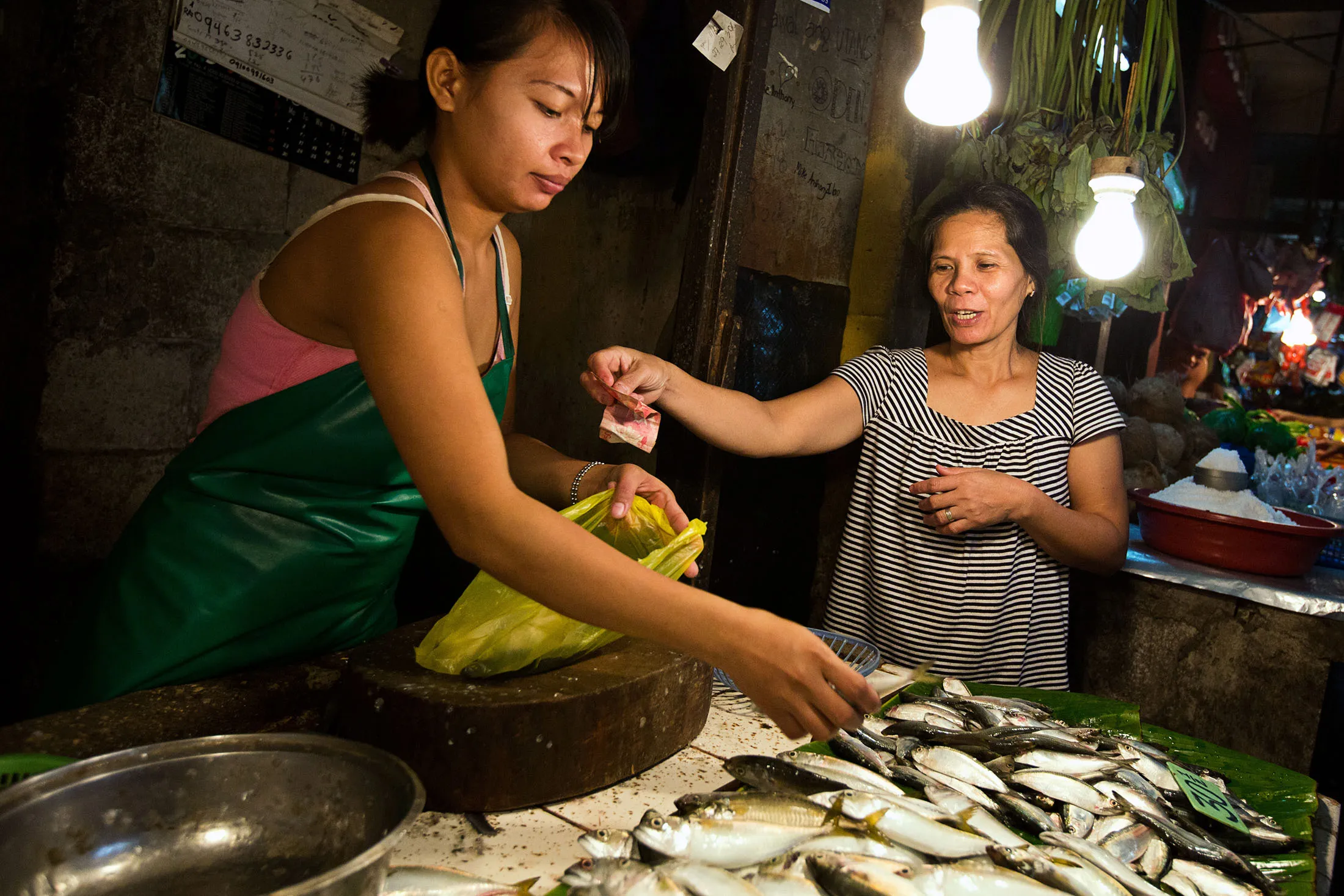 A customer hands over Philippine peso banknotes to a fishmonger at a market stall in the Tondo district of Manila.
