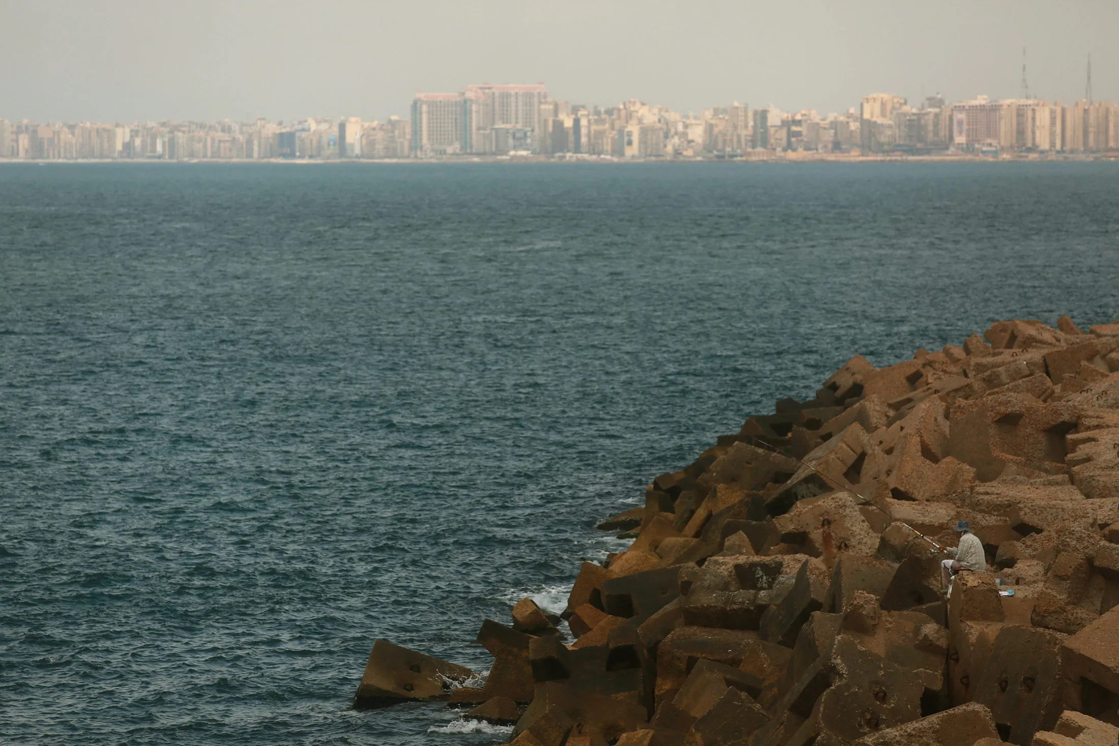 A fisherman looks out over the Mediterranean Sea from the coastline of Alexandria.
