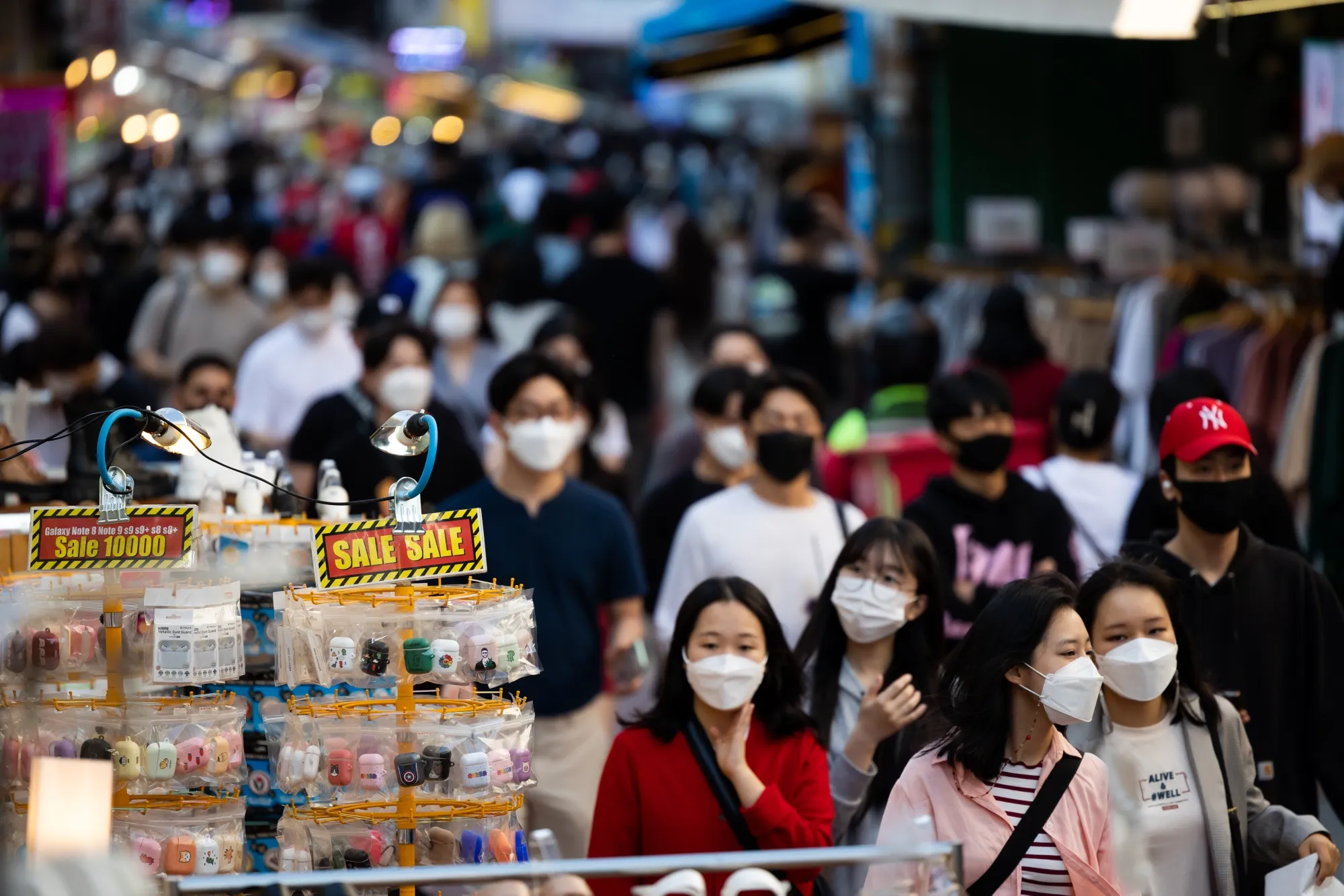 People wearing masks walk through the Hongdae shopping district in Seoul.