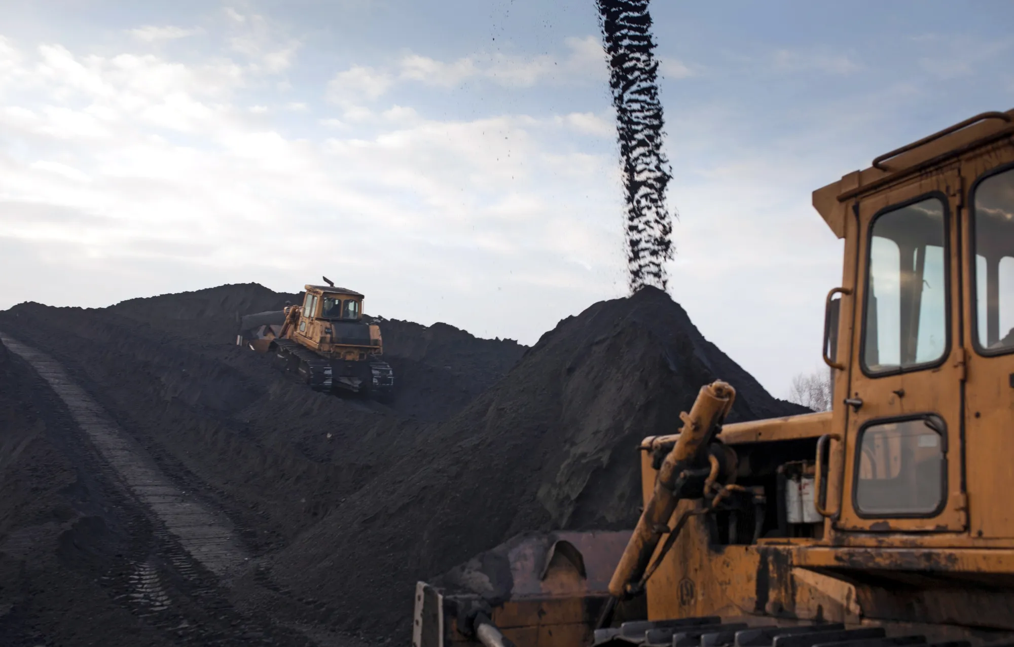 Bulldozers arrange stores of coking coal in a storage dump at the Bielszowice mine, operated by Kompania Weglowa SA, in Ruda Slaska, Poland, on Thursday, Feb. 5, 2015. Silesia's 100,000 miners dig some 140 million metric tons of coal a year.
