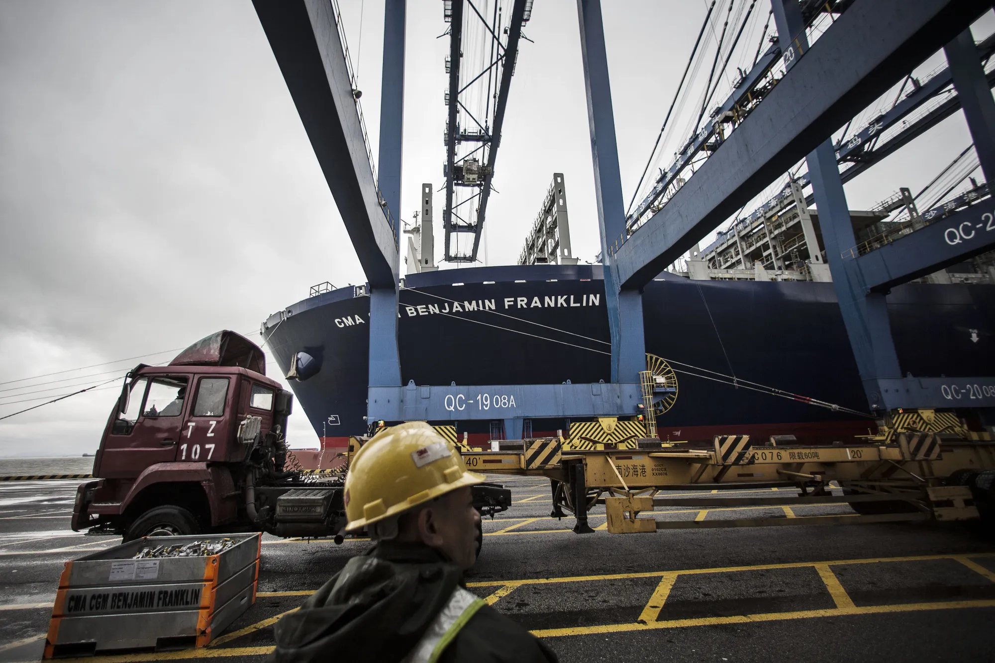 A dock worker directs the loading of shipping containers&nbsp;in Guangzhou, China.