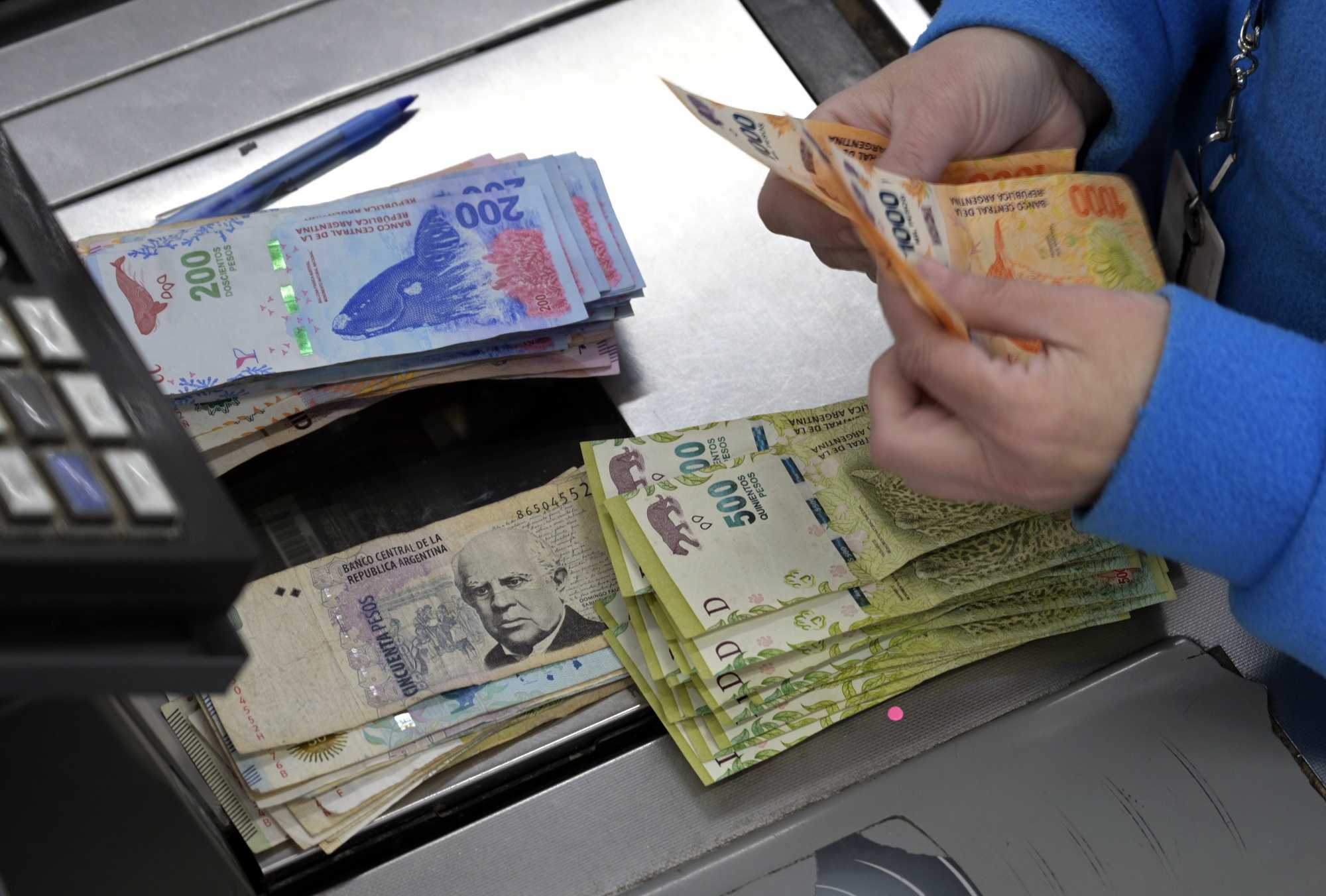 A cashier counts Argentine pesos&nbsp;in Buenos Aires, Argentina.&nbsp;