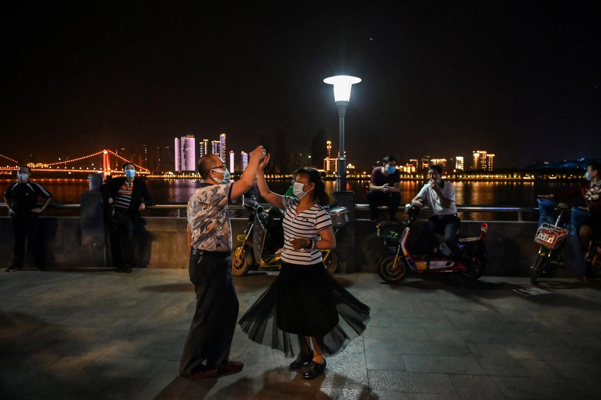A couple wearing facemasks dance in a park next to the Yangtze River in Wuhan, on May 12.