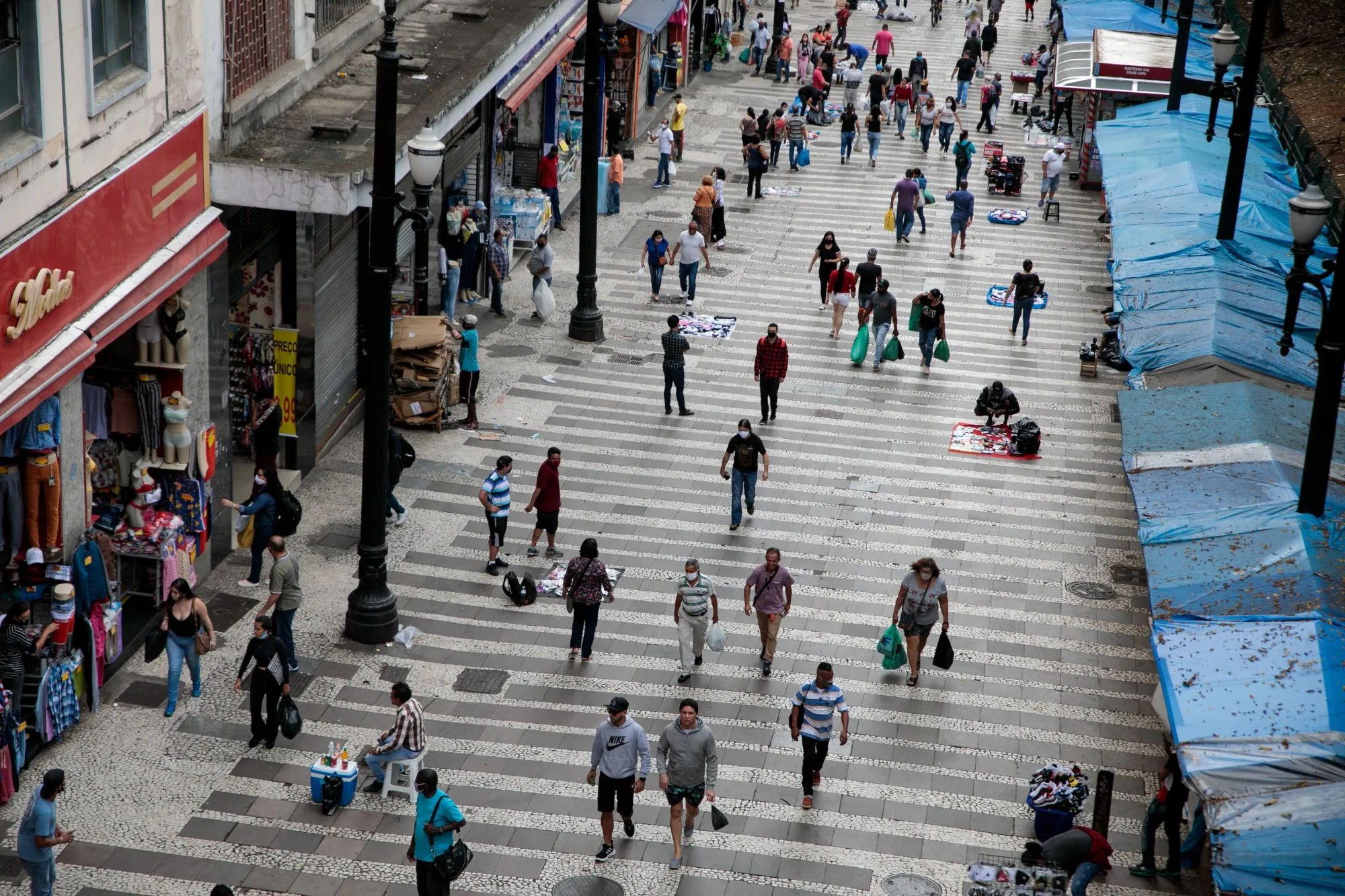 People wearing protective masks carry shopping bags while walking through downtown Sao Paulo, Brazil, on June 10.