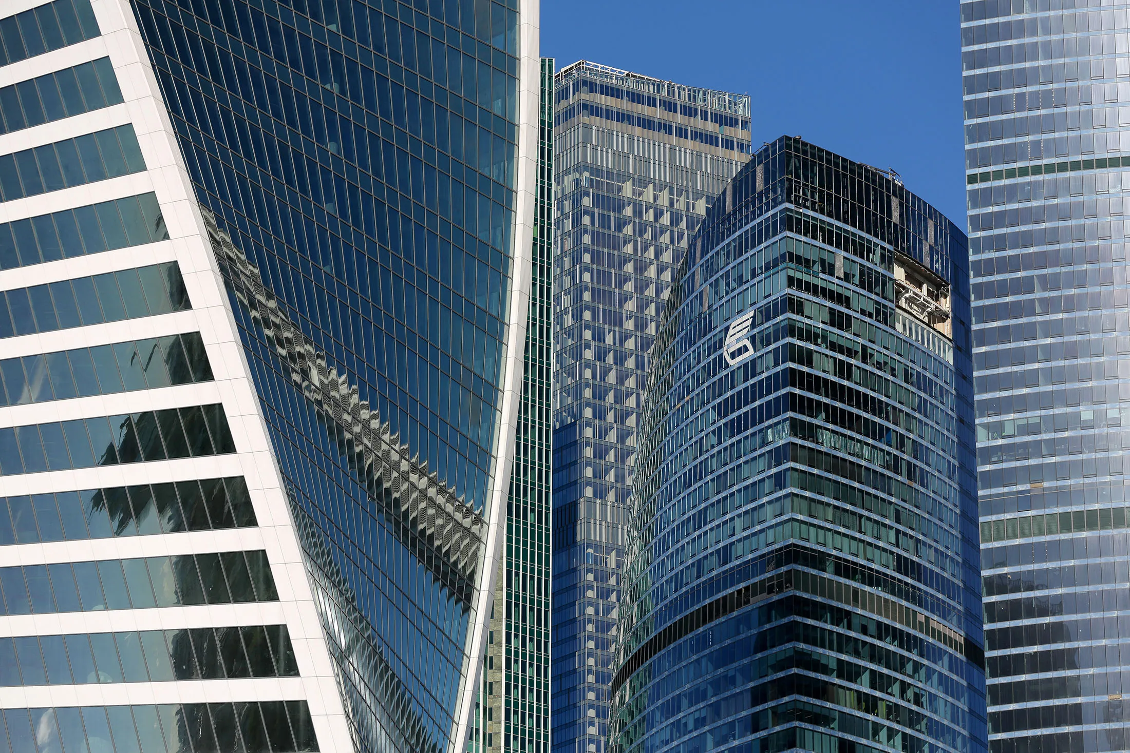 A logo sits on display outside the office tower of VTB Bank, center, between city skyscrapers in the Moscow International Business Center.
