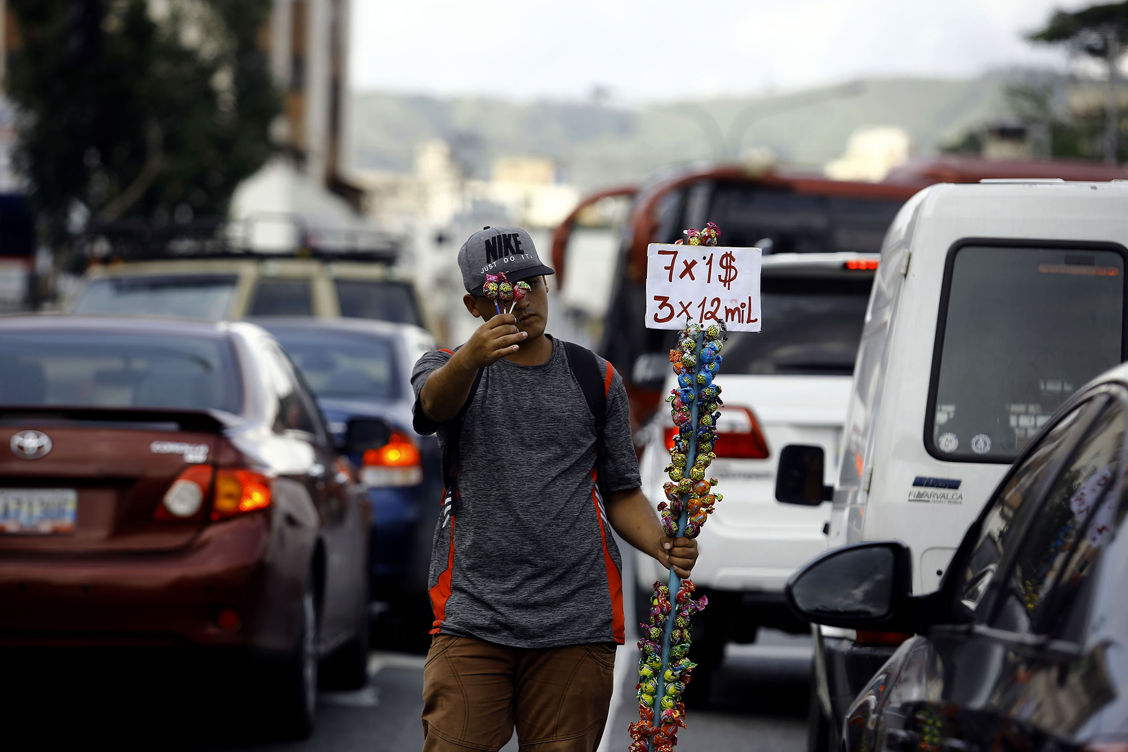 A young man peddles candy priced in dollars and bolívares at a traffic light in Valencia, Venezuela, on Nov. 1, 2019.