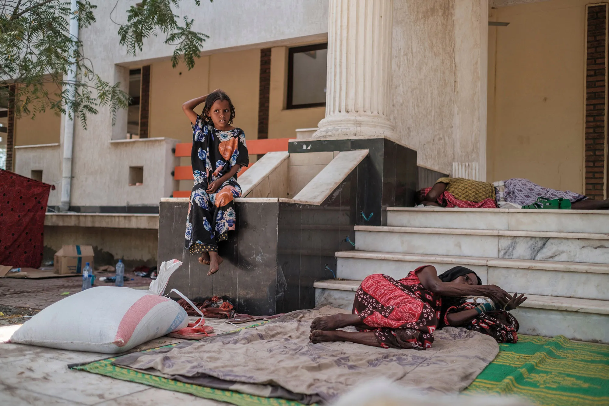People rest at the entrance of the Agda Hotel, in Semera, Afar region, after fleeing violence.&nbsp;