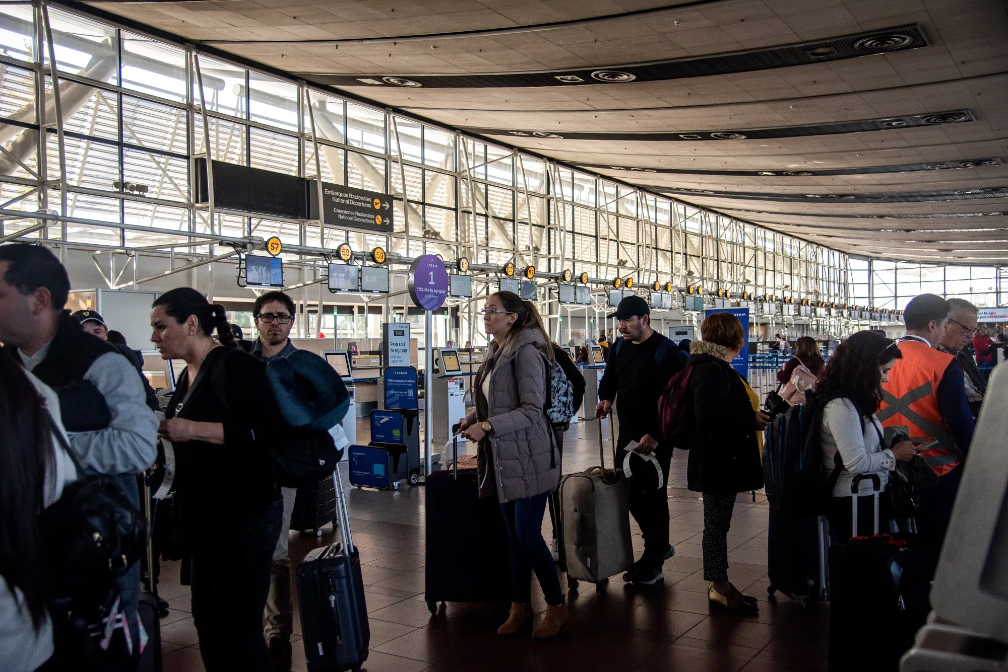 Travelers arrive at the Latam Airlines check-in counter at Arturo Merino Benitez International Airport (SCL) in Santiago, Chile.