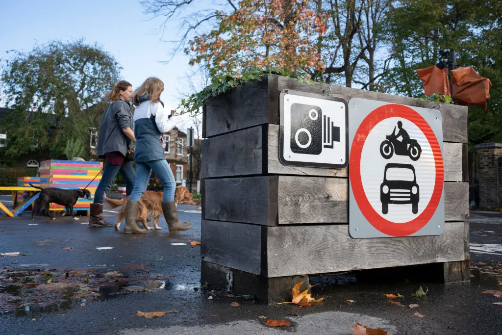 Pedestrians pass planter barriers that form a Low Traffic Neighbourhood&nbsp;road closure feature by Southwark Council.&nbsp;