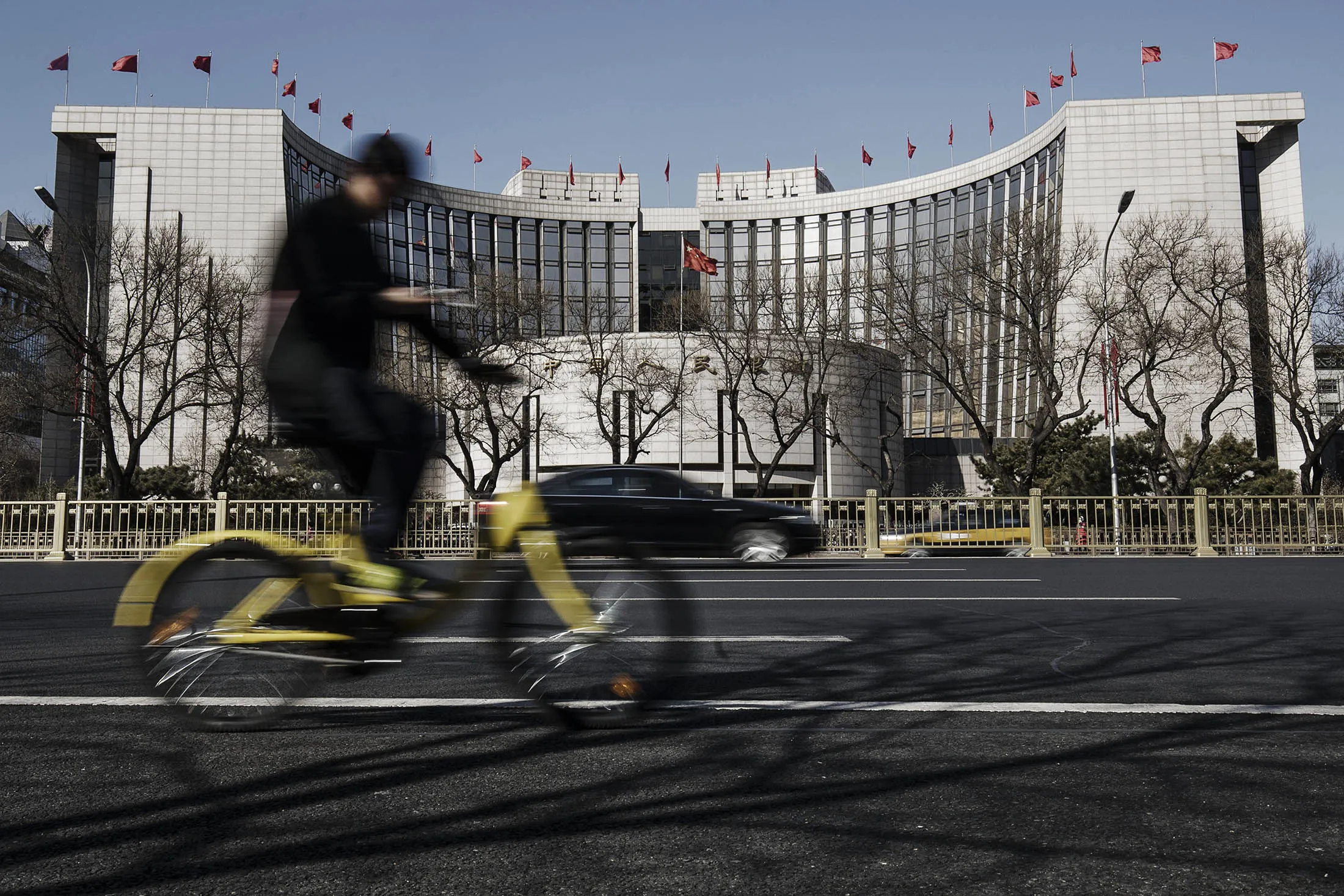 A man rides a bicycle past the People's Bank of China headquarters in Beijing.