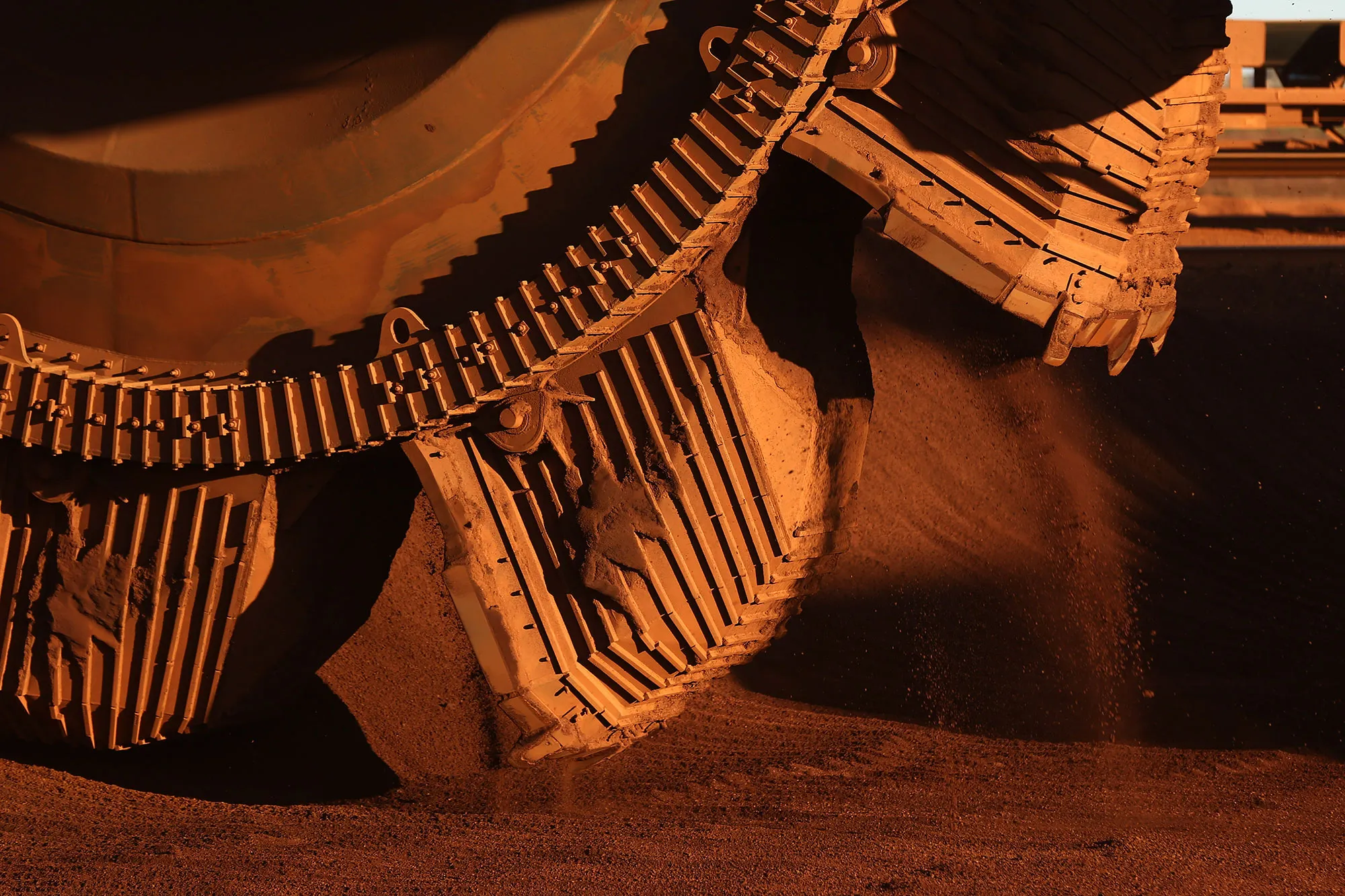 A bucket wheel reclaimer collects iron ore from a stockpile.
