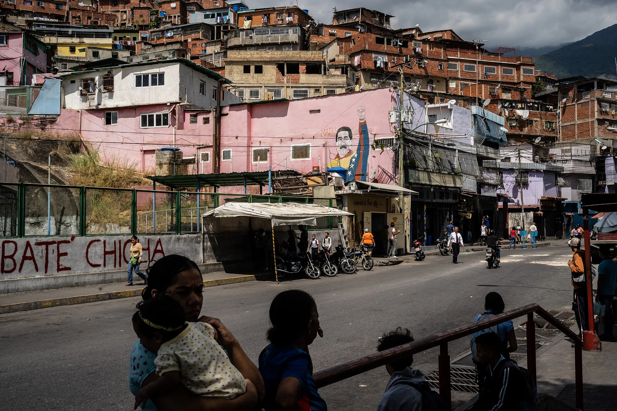 Children pass a mural of Maduro, at the entrance of the José Félix Ribas neighborhood, in the Petare Slum.