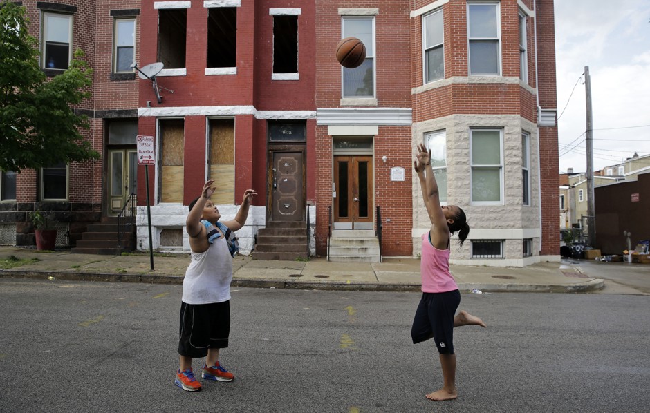 Children play with a basketball in front of a vacant home, left, and a restored home in the Reservoir Hill neighborhood of Baltimore on May 10, 2015.