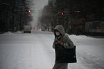 A woman wearing a face mask crosses a street during snowfall in Sapporo, northern Japan on Feb. 3.