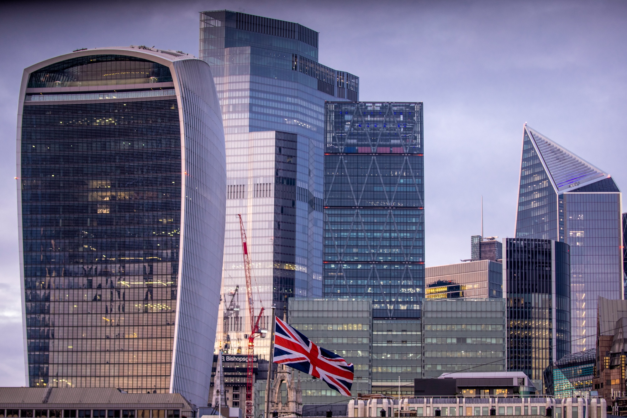 A British Union flag flies in view of skyscrapers in the City of London.