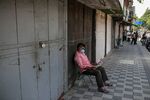 A man reads newspaper outside closed stores in a near-empty street during lockdown in Pune, Maharashtra, earlier in May.