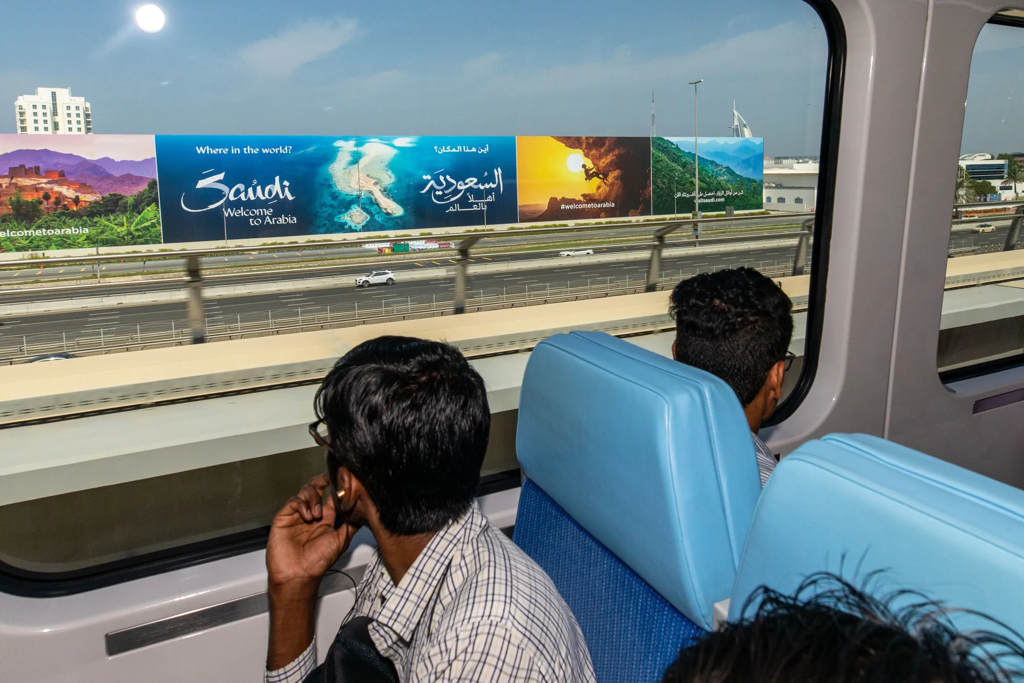 Dubai Metro passengers pass a billboard for the Saudi tourist board on Oct. 18.