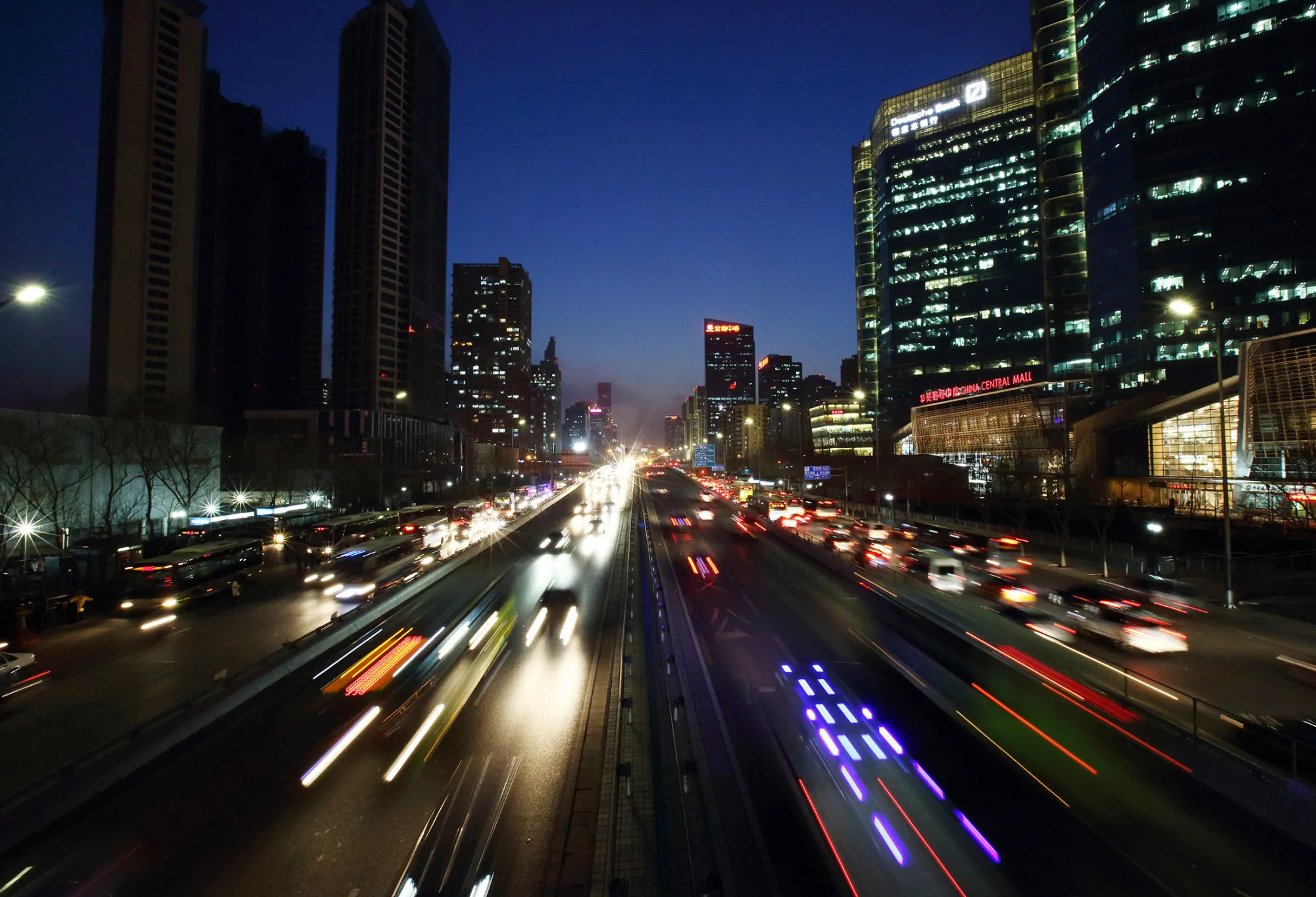 Vehicles move along an expressway as towers at Kaisa Plaza, developed by Kaisa Group Holdings Ltd., left, stand near completion at night in Beijing, China, on Tuesday, March 10, 2015. China set the lowest economic growth target in more than 15 years and flagged increasing headwinds that include a property slump, excess industrial capacity and disinflation.
