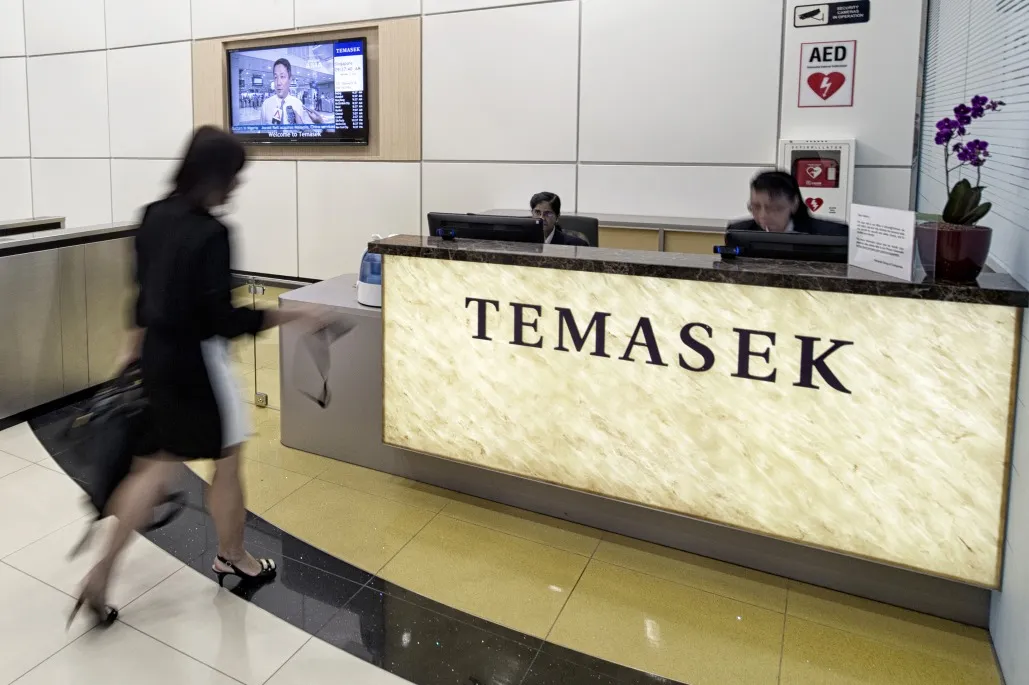A woman approaches a counter displaying signage for Temasek Holdings Pte in the lobby at the company's headquarters in Singapore.