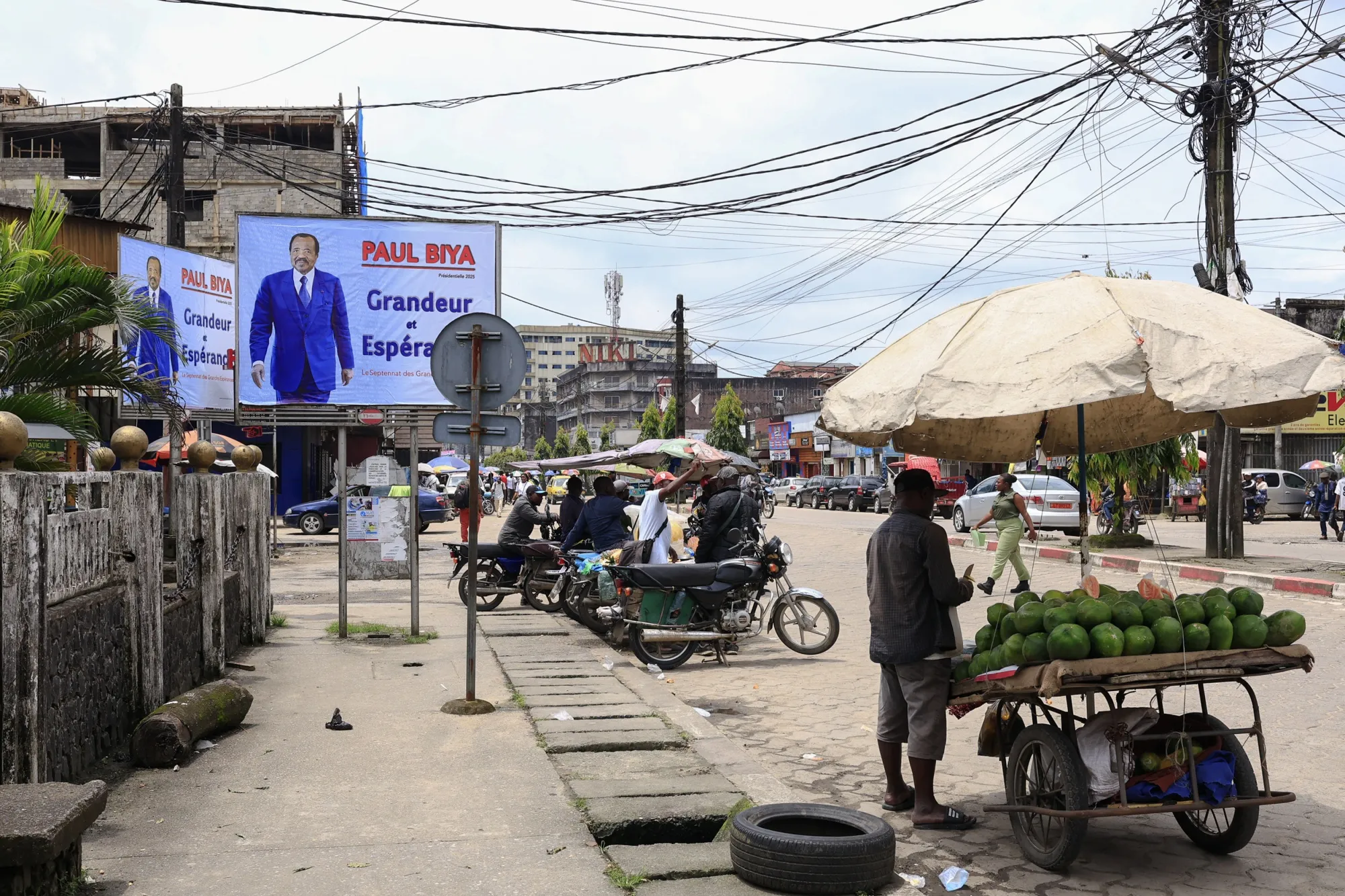 Pedestrians walk past a campaign billboard of Cameroon's President Paul Biya in Douala, Cameroon on Oct. 6, 2025.