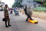 A Sri Lankan security personnel kicks a burning tire thrown by demonstrators to block a road during a protest in Colombo on June 7.